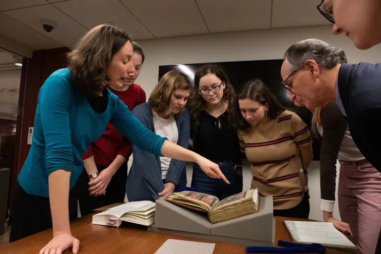 Students surrounding a 13th century book. 