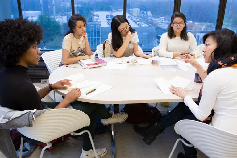 Students sitting around a table reading 