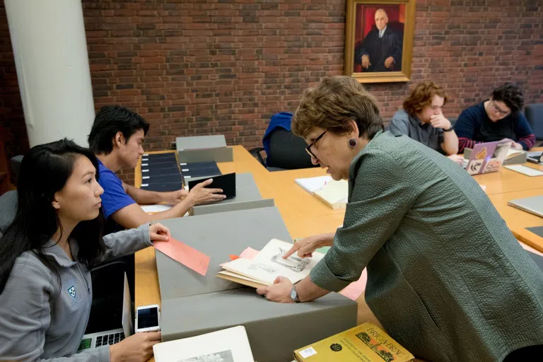 A student getting help from a staff member who is pointing at a book