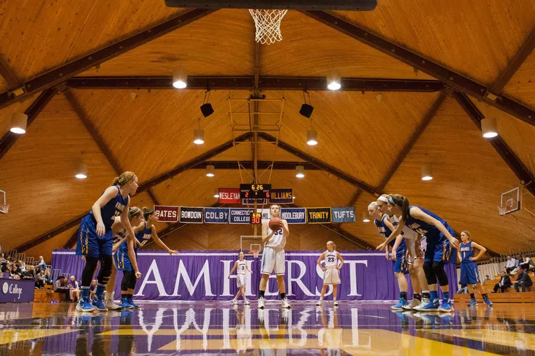 Inside shot of LeFrak Gymnasium with peaked roof and women's basketball team playing.