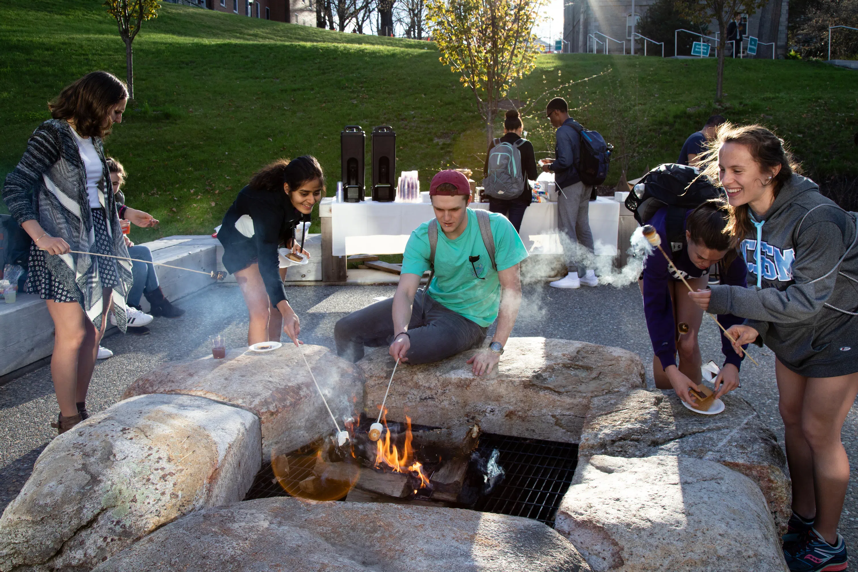 Students roasting marshmallows by fire pit