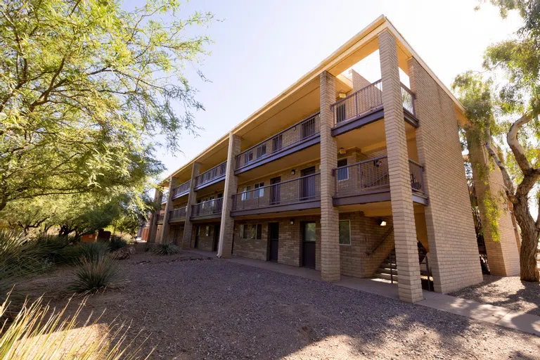 A three-story brown building with exterior walkways and railings.