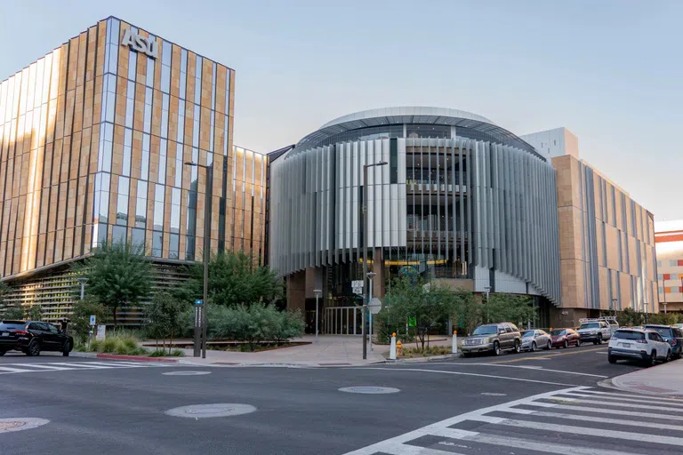 Three-story rounded silver building with a six-story tan building to its left and ASU logo at the top.