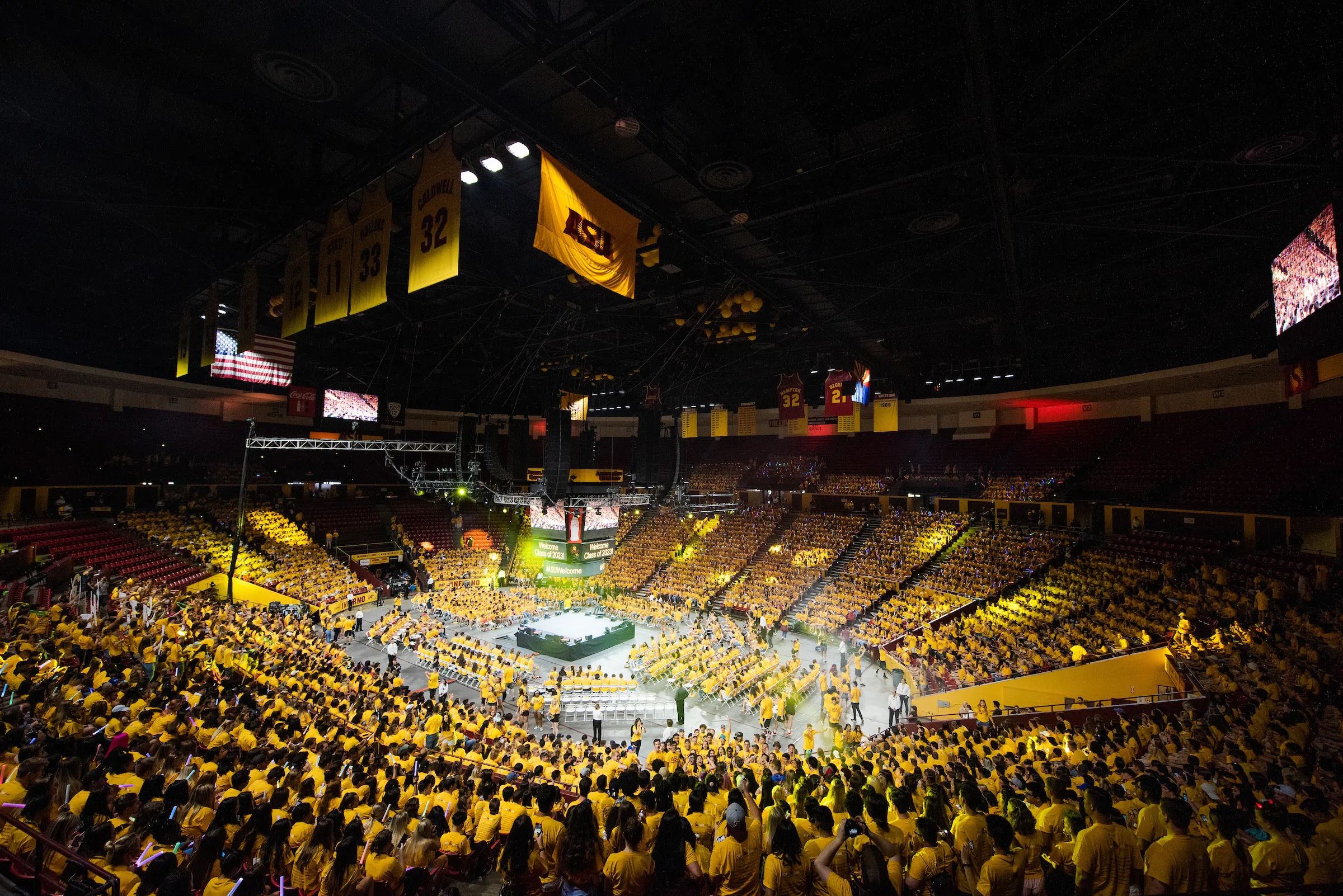 Inside arena full of students wearing gold with a stage in the center of the room during Sun Devil Welcome event.