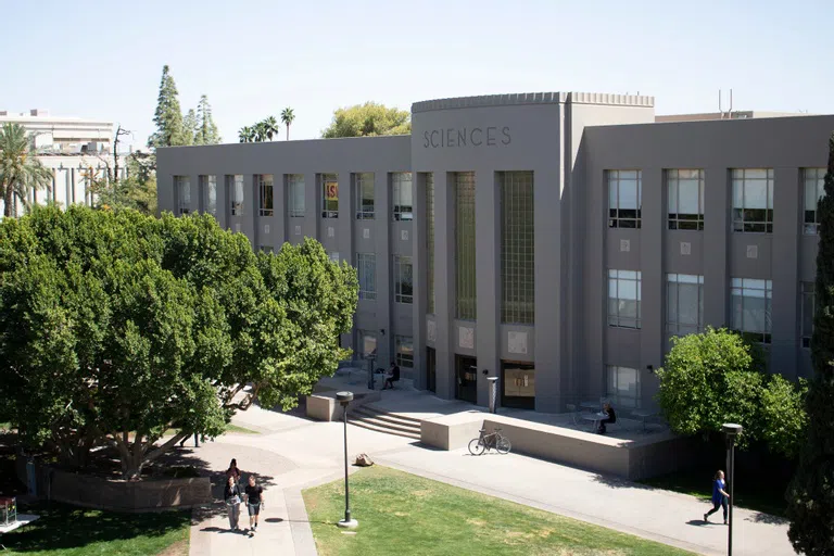 Four stairs lead up to a three-story gray building with the word "sciences" across the top of it. 