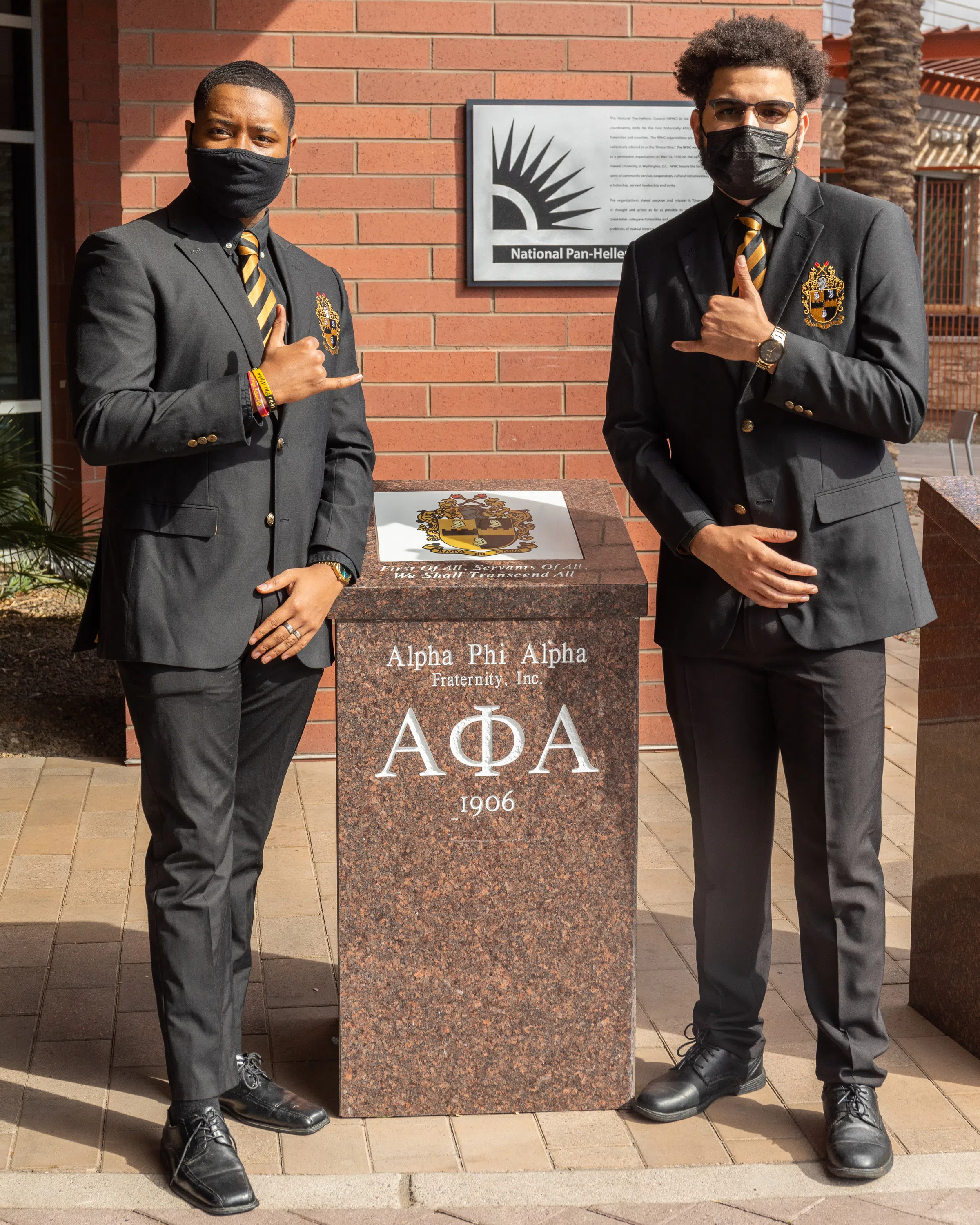 Two representatives from the Alpha Phi stand in front of the society's plaque. 