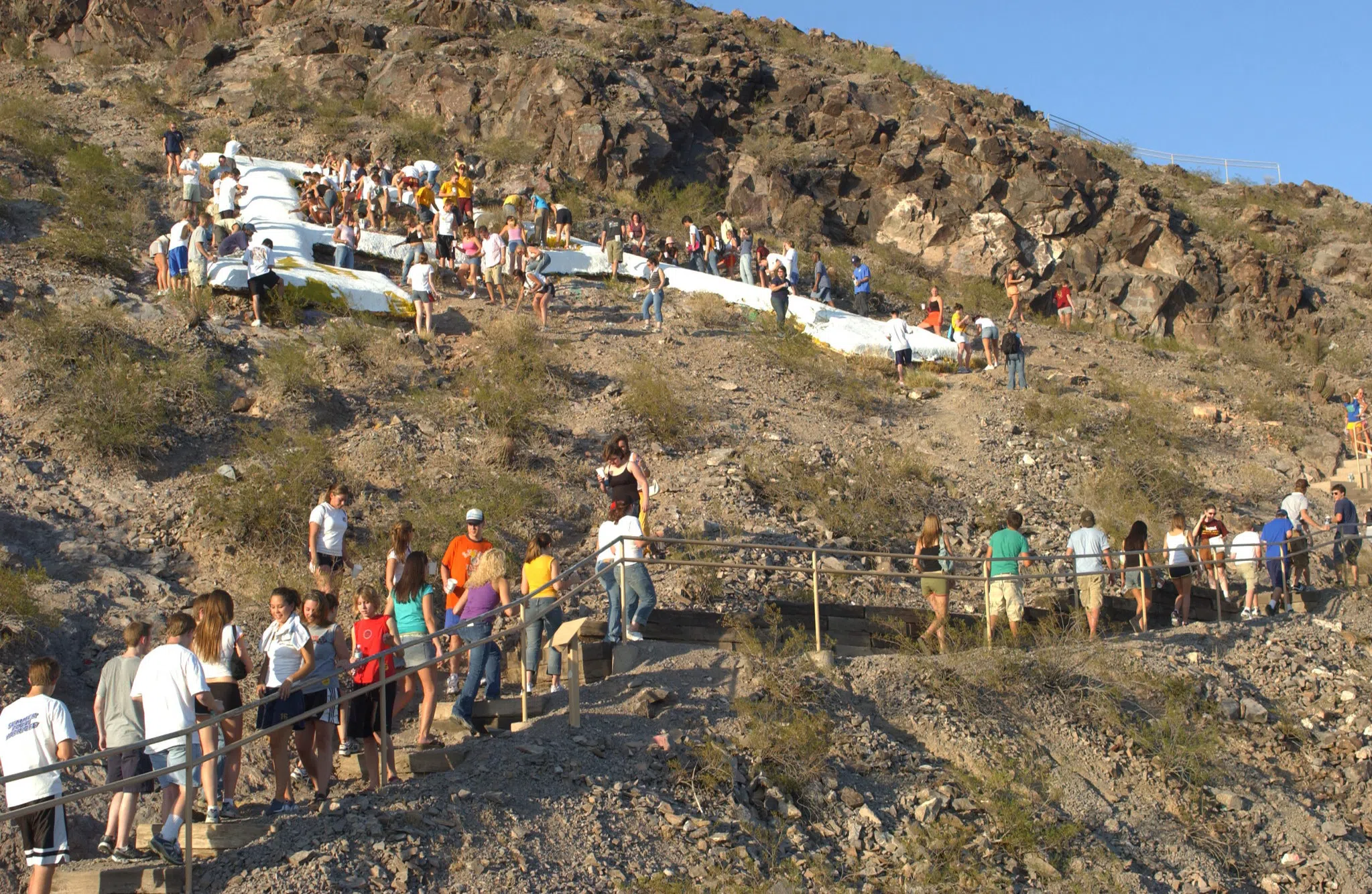 A line of students painting the "A" on "A" mountain white.