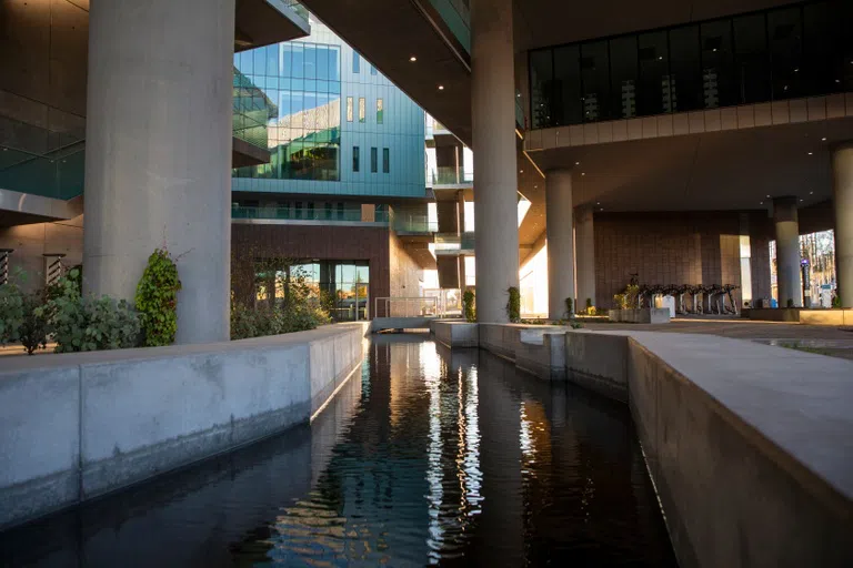 A canal of water runs through a concrete and glass building.