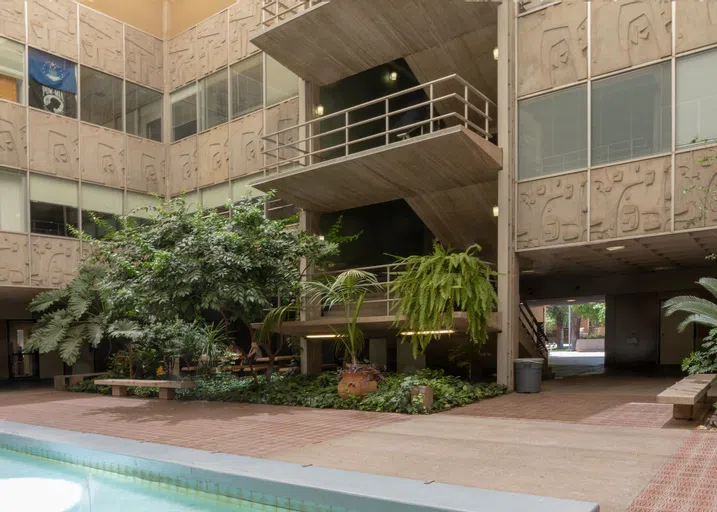 a fountain and trees are in an atrium of a three-story concrete building