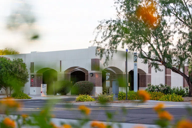 Yellow flowers blur in the foreground of a brick and stucco building with arched courtyard. 