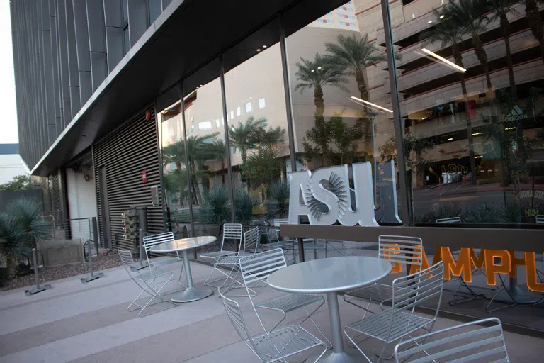 Silver metal tables and chairs on patio in front of ASU Campus Store sign on a glass window. 