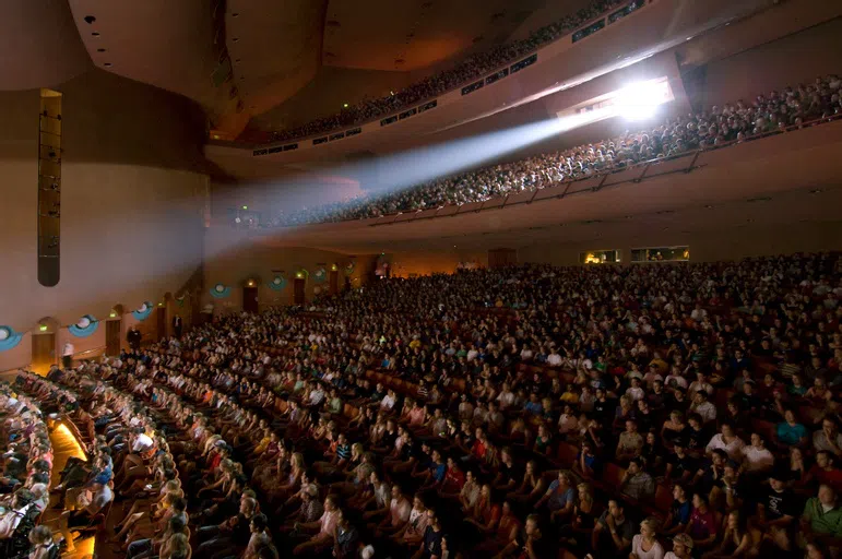 View of three tiers of audience members watching an event on stage. 