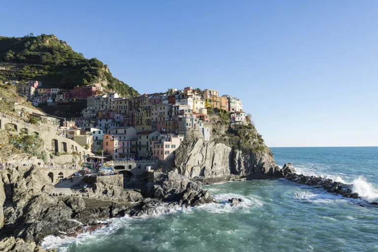 The Italian village of Manarola features tall and vibrant houses perched on a cliff over the sea.