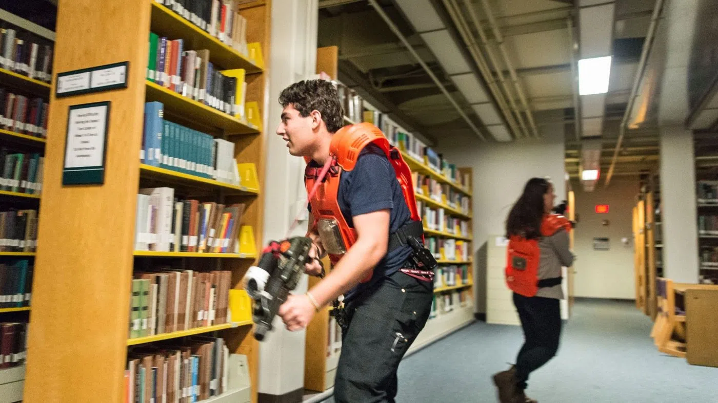 Two students in the midst of a laser tag game between the stacks of Ladd Library