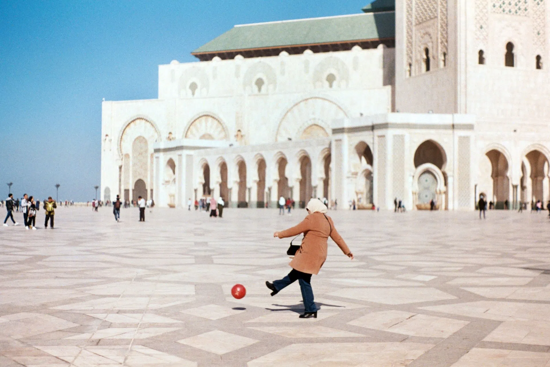 A mother plays soccer with her son outside the Hassan II Mosque.