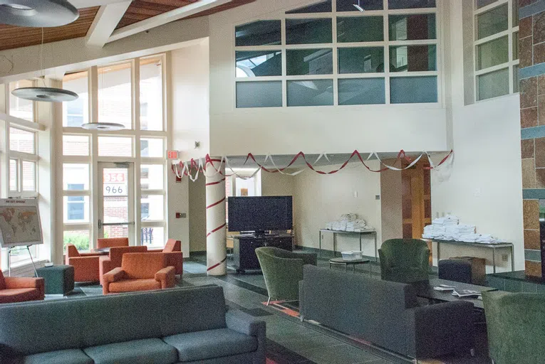 The living room of 280 College Street holds several gray and orange couches for residents to gather.