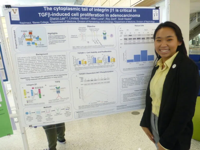 Student stands with a research poster.