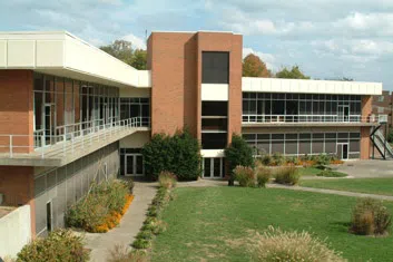 Large modern red brick building with wrap-around covered porches and lots of windows. 