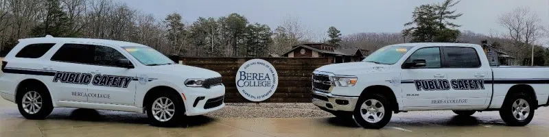 two trucks with public safety logos on them sit near a Berea College logo