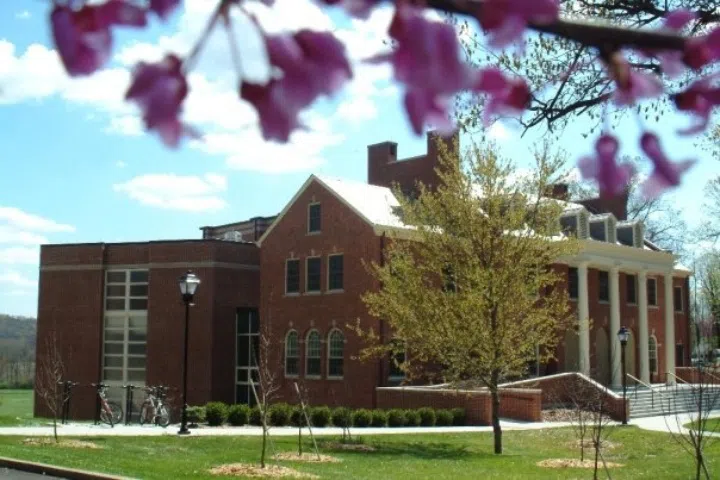 Exterior of large red brick building with large white columned portico and entry.