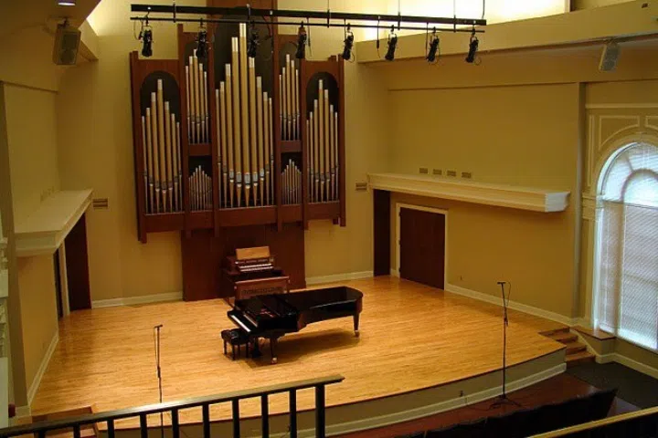 Interior shows stage with grand piano and pipe organ