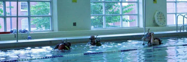 Three students in scuba diving gear test the water in our indoor pool.