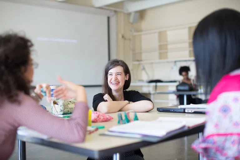 Professor listens to student while in a classroom