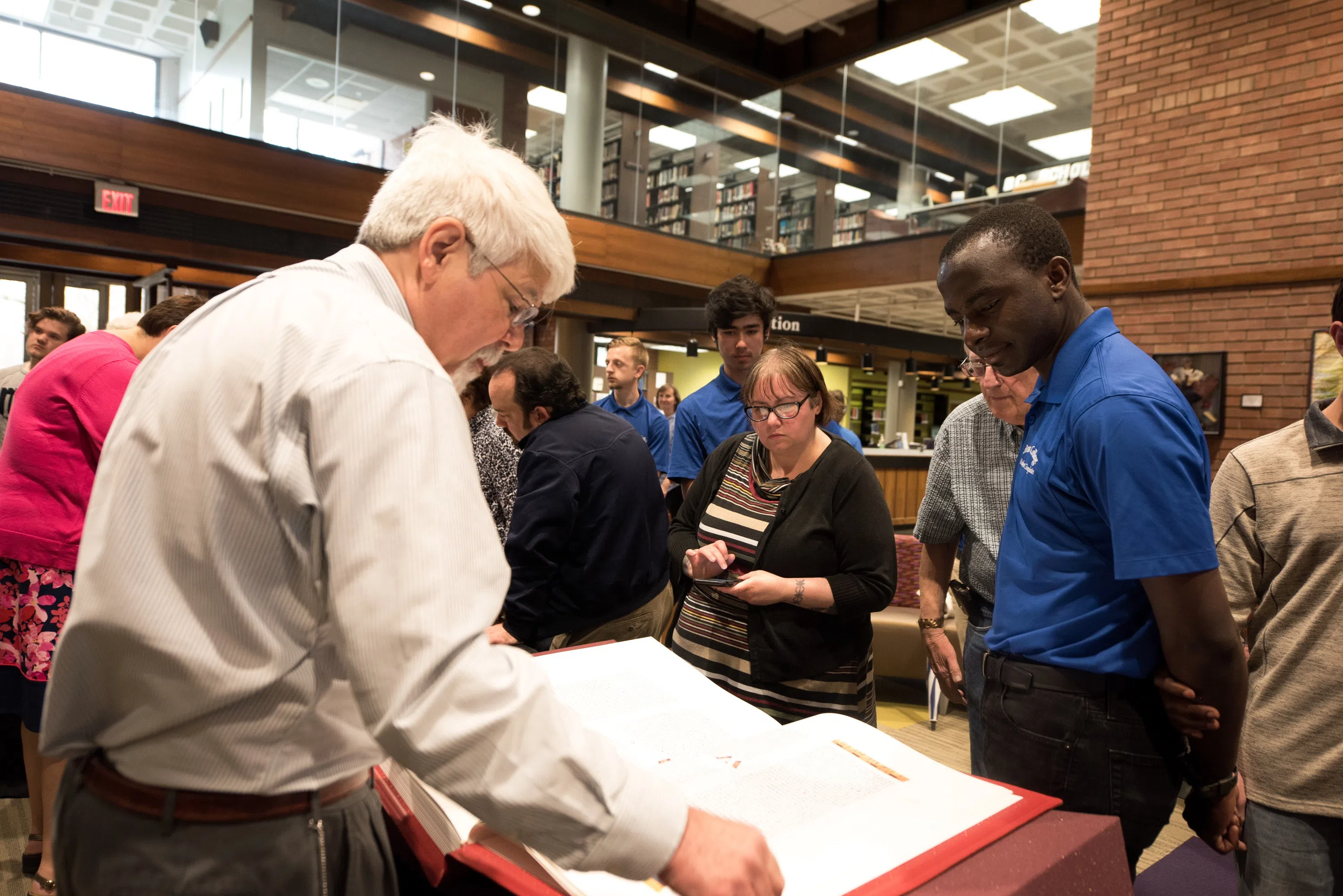Students look over the St. Johns Bible in the atrium of the library.