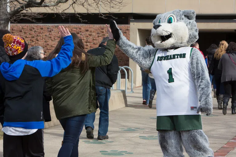 Baxter the Bearcat greets students with a high five.