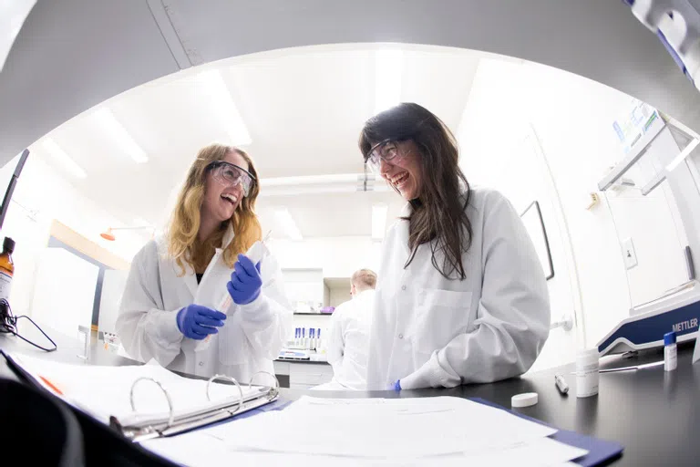 Students working in a lab in white lab coats.