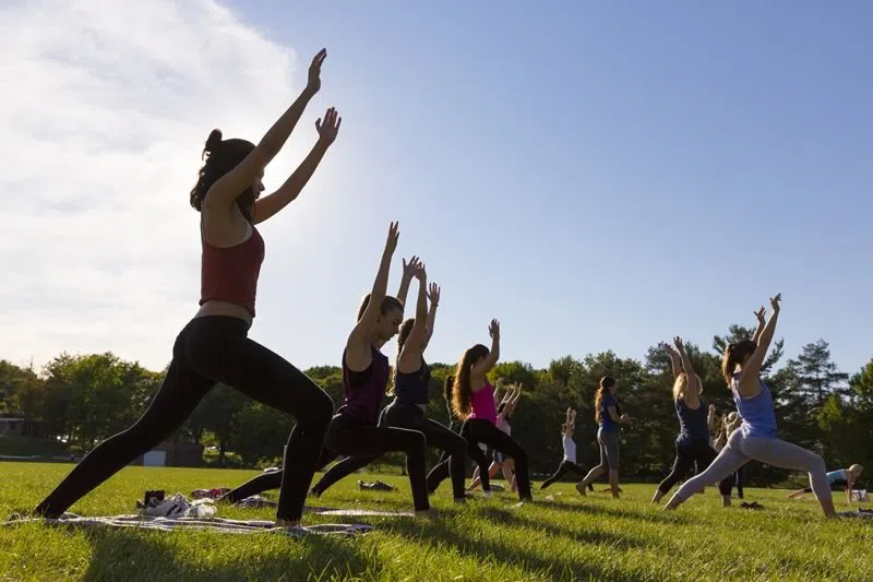 Students participating in a yoga group fitness class outdoors