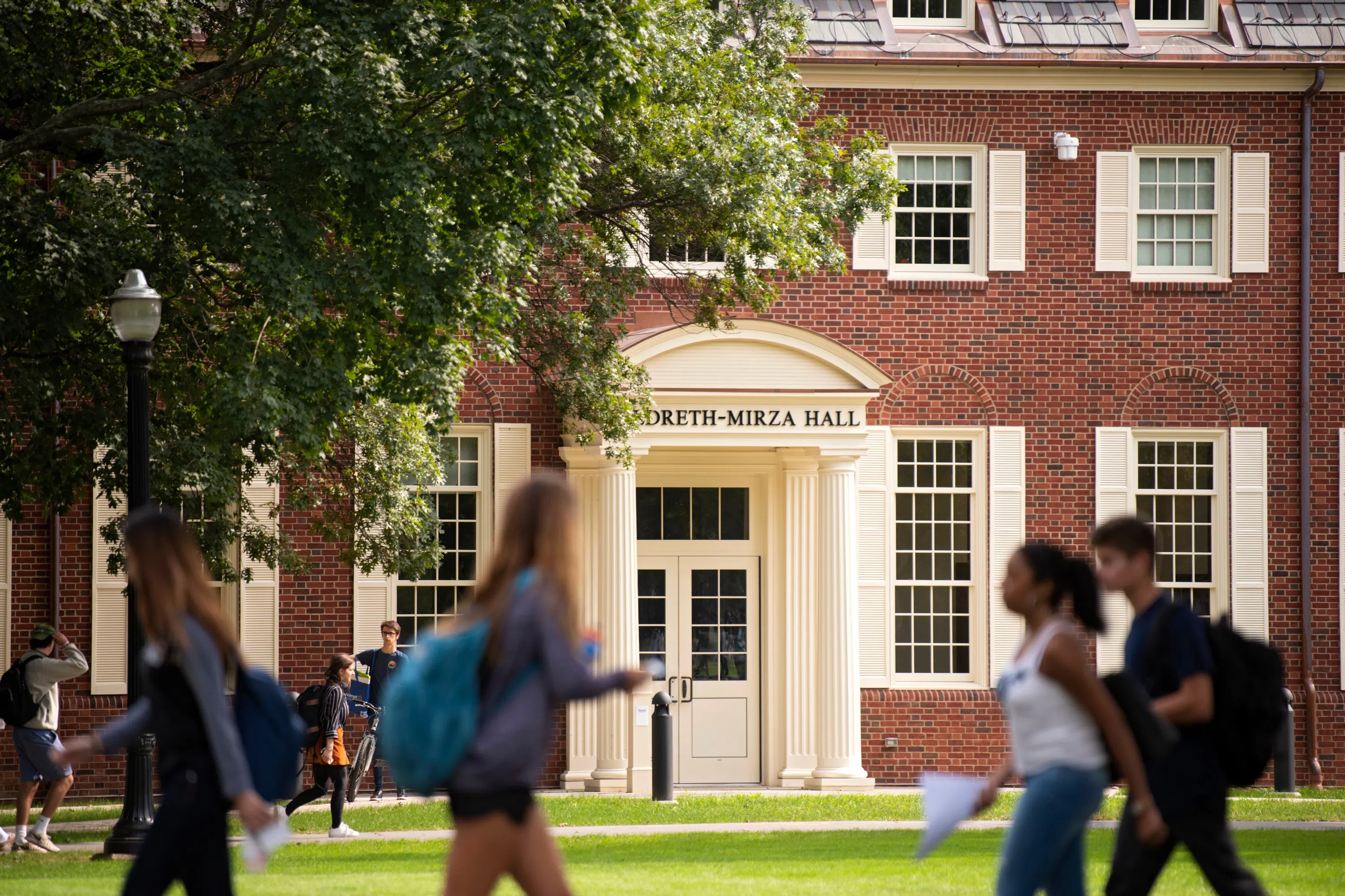 students walk past the front exterior of Hildreth-Mirza Hall