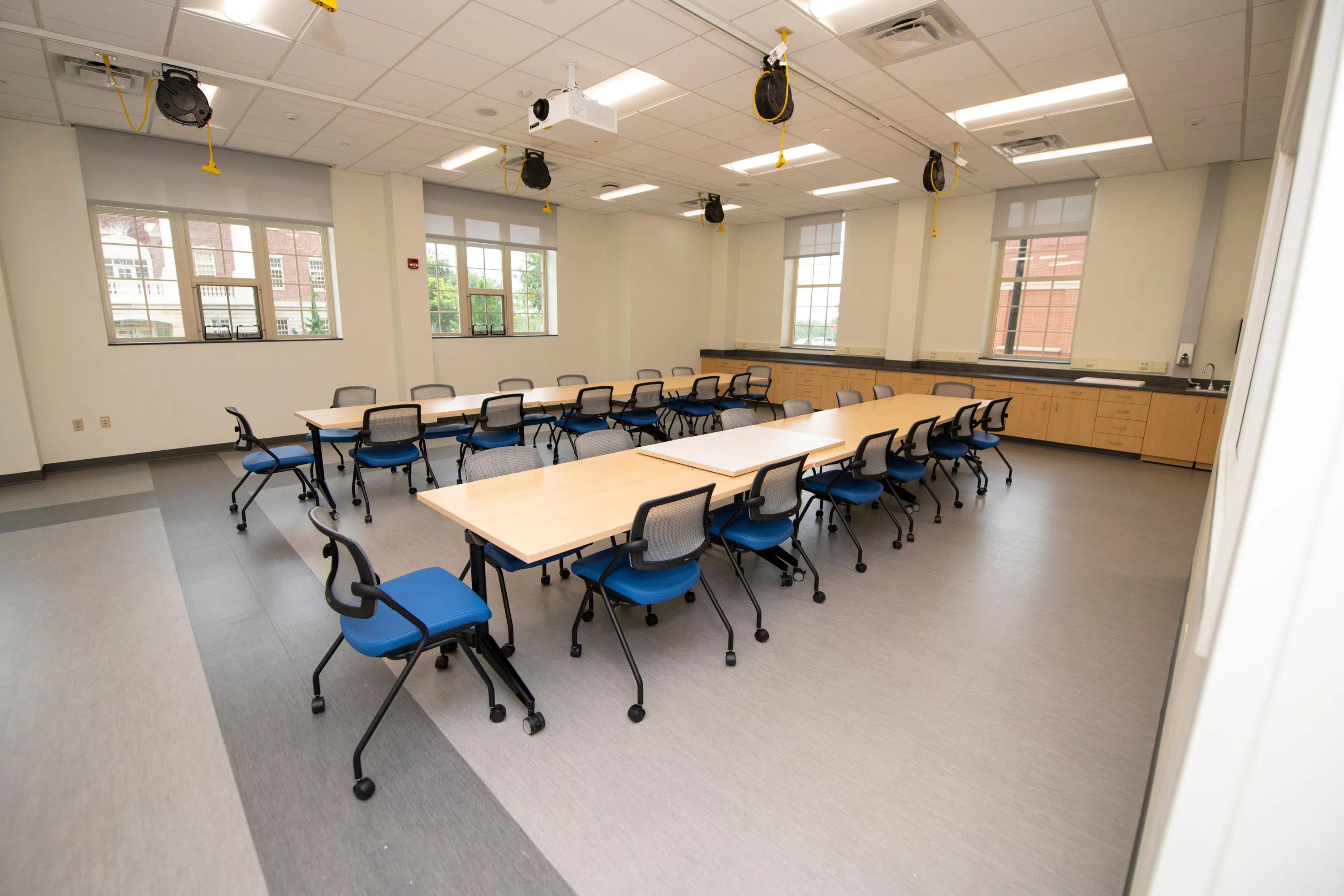 a classroom with two long conference tables, each surrounded by 14 chairs