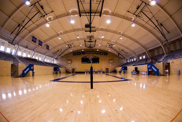 a volleyball court at ground level, with a team in the background against the far wall