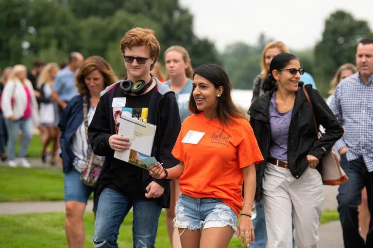 A close-up of a  female tour guide and the group she's leading on the quad