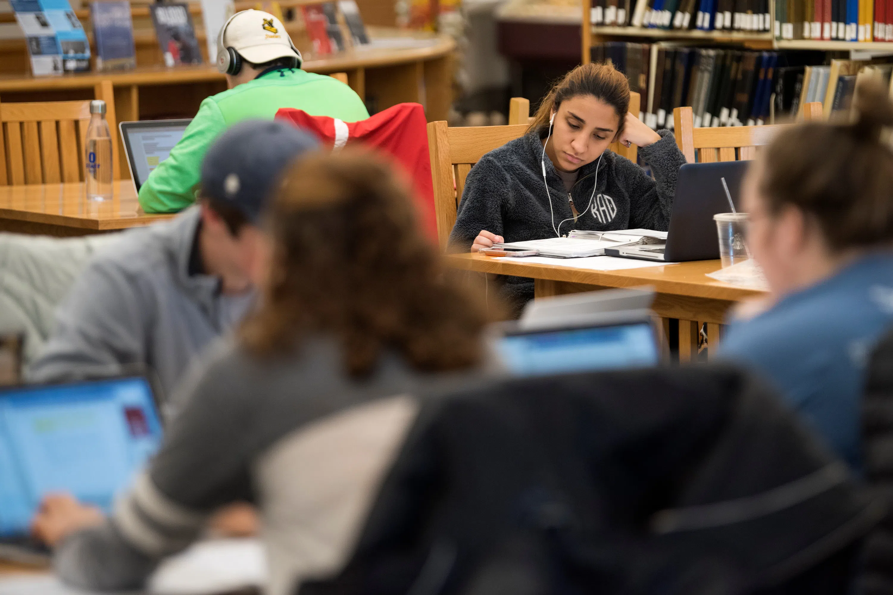 Several groups of students study in the library at several tables