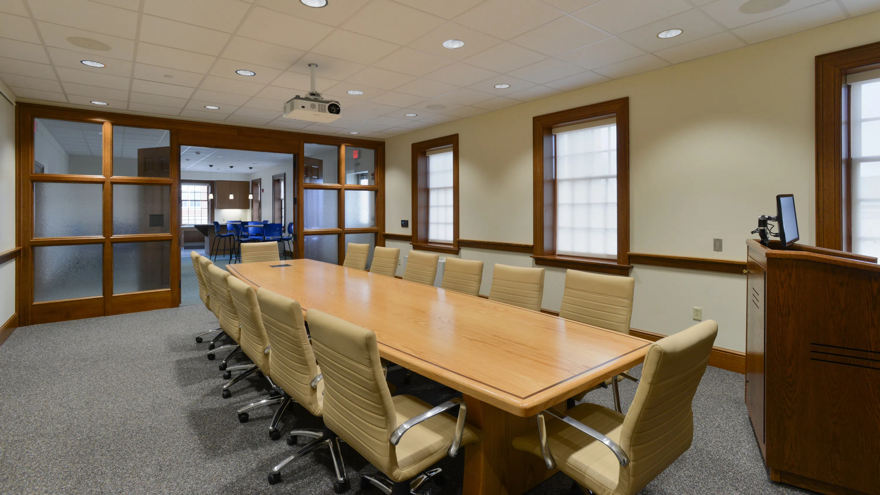 a long conference table with 14 chairs surrounding it and a podium in the foreground in a conference room