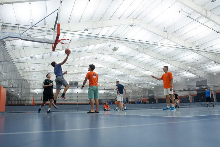 a male student goes in for a layup playing basketball with other students