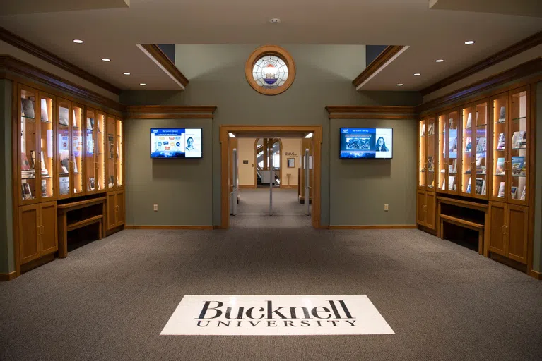 vestibule of bertrand library - bucknell university logo on the floor, built-in bookshelves with books on either side