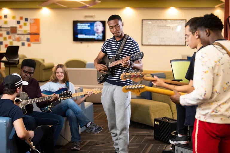 6 students strum guitars