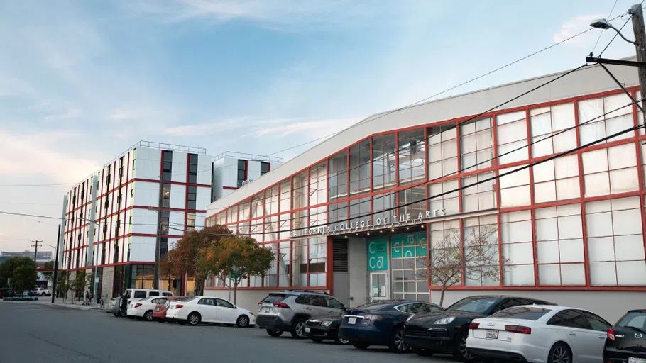 Pedestrian view of the Main Building with cars lined up in front. 