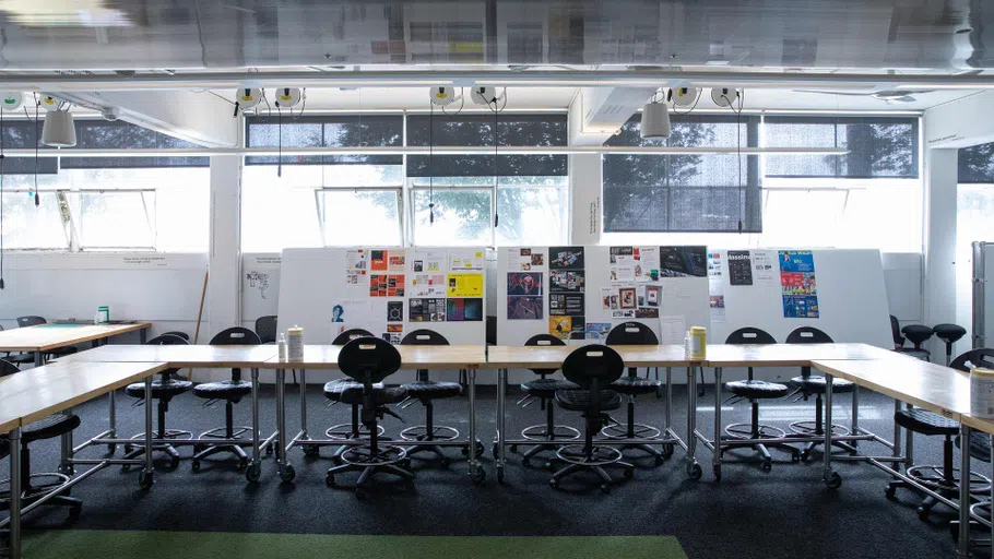 An empty room with a long table, chairs, and white board behind it.