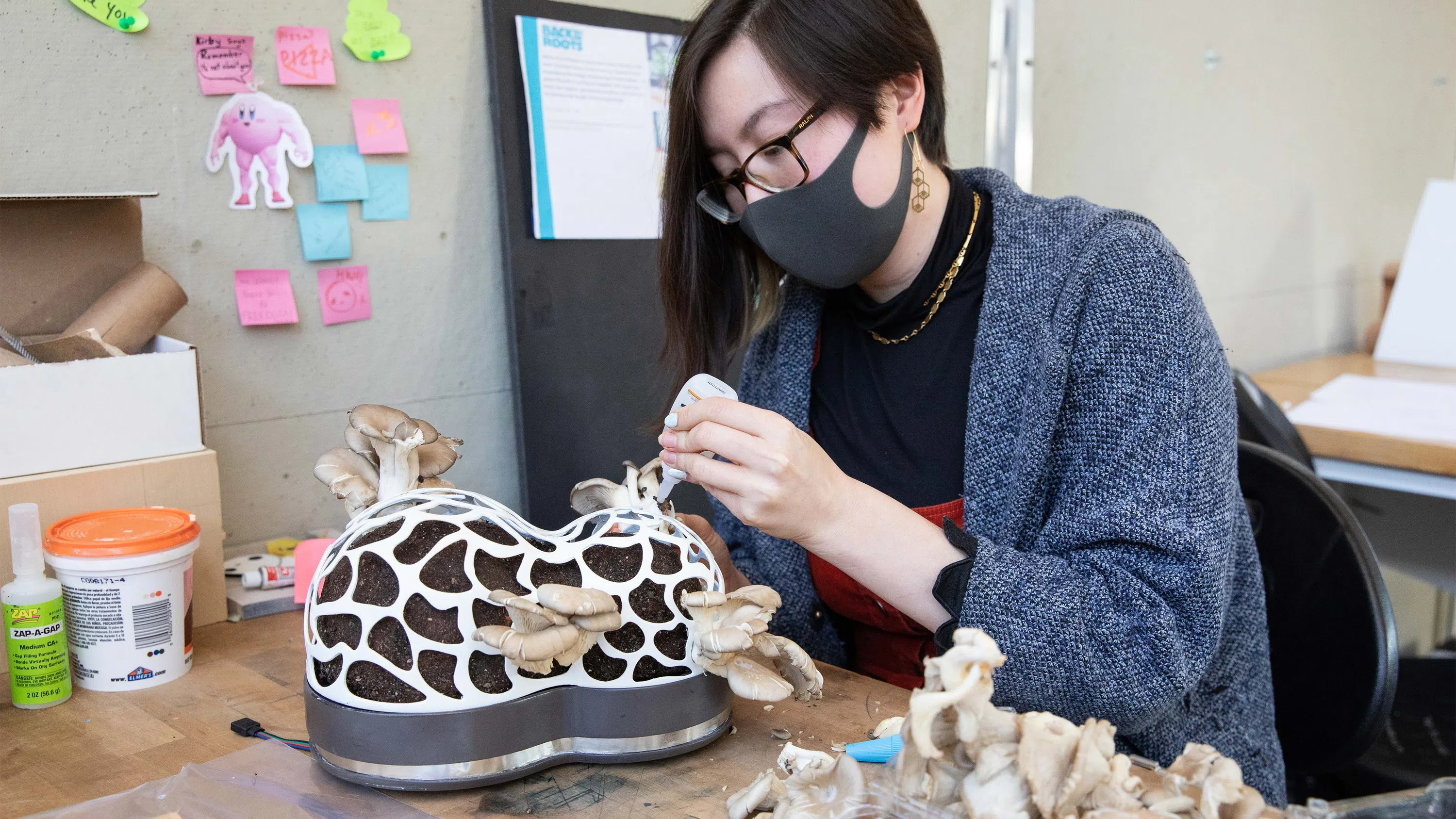 A student glues mushrooms onto an organic sculpture in the Industrial Design studios.