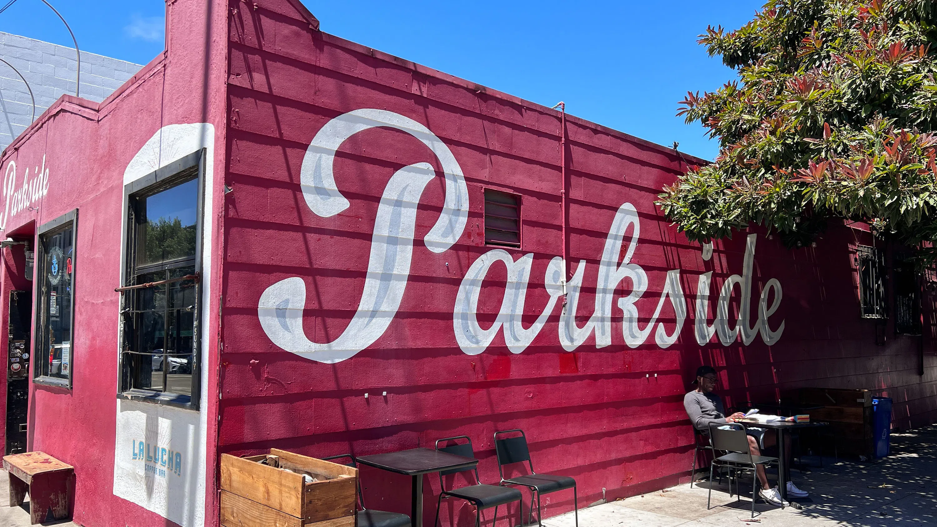 Exterior view of Thee Parkside bar - a building painted in red with white lettering painted on the side. 