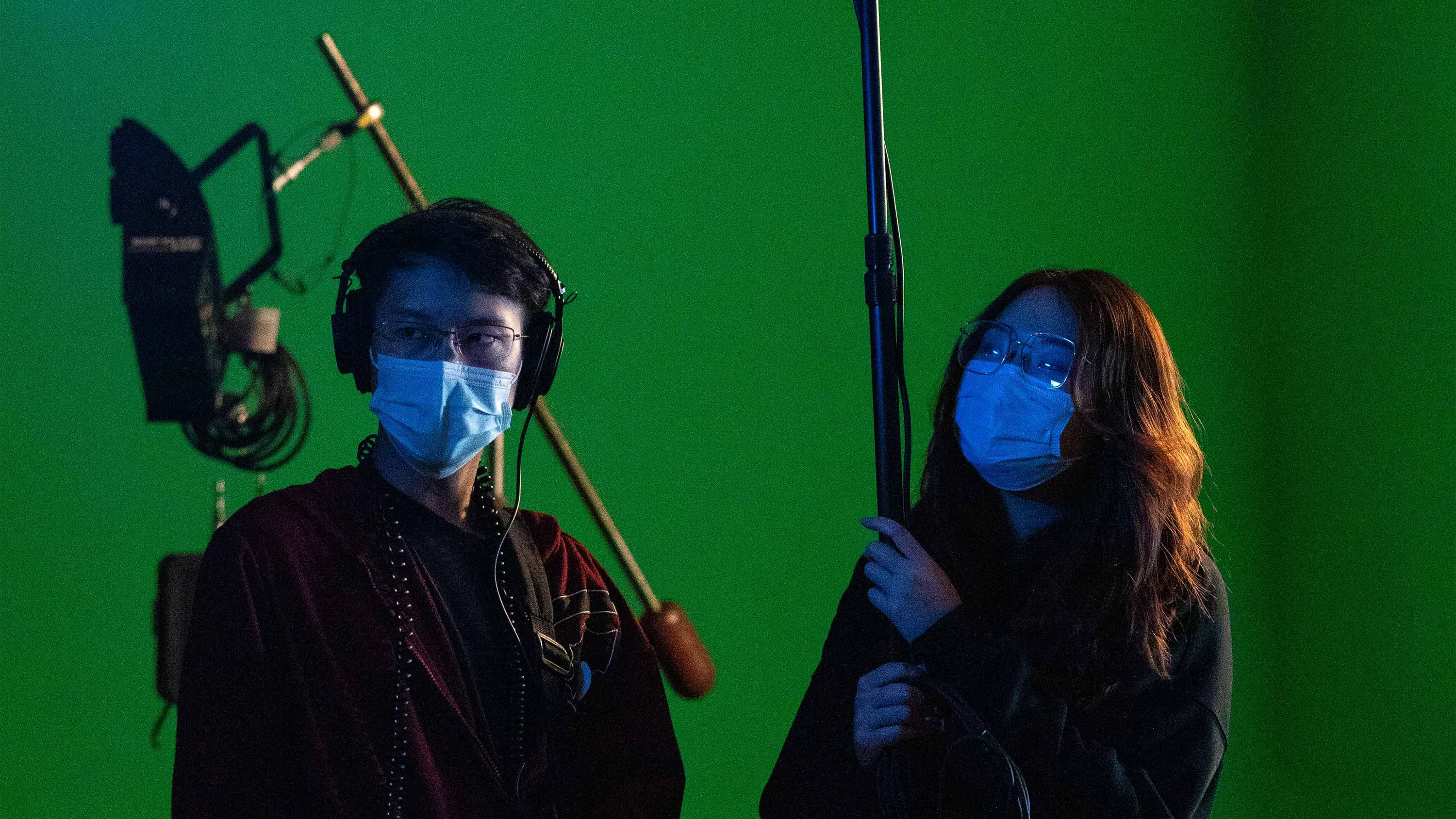 Two students holding boom mics on the production stage.