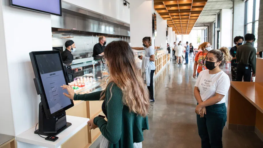 A person orders online at a stanchion in the busy cafe.