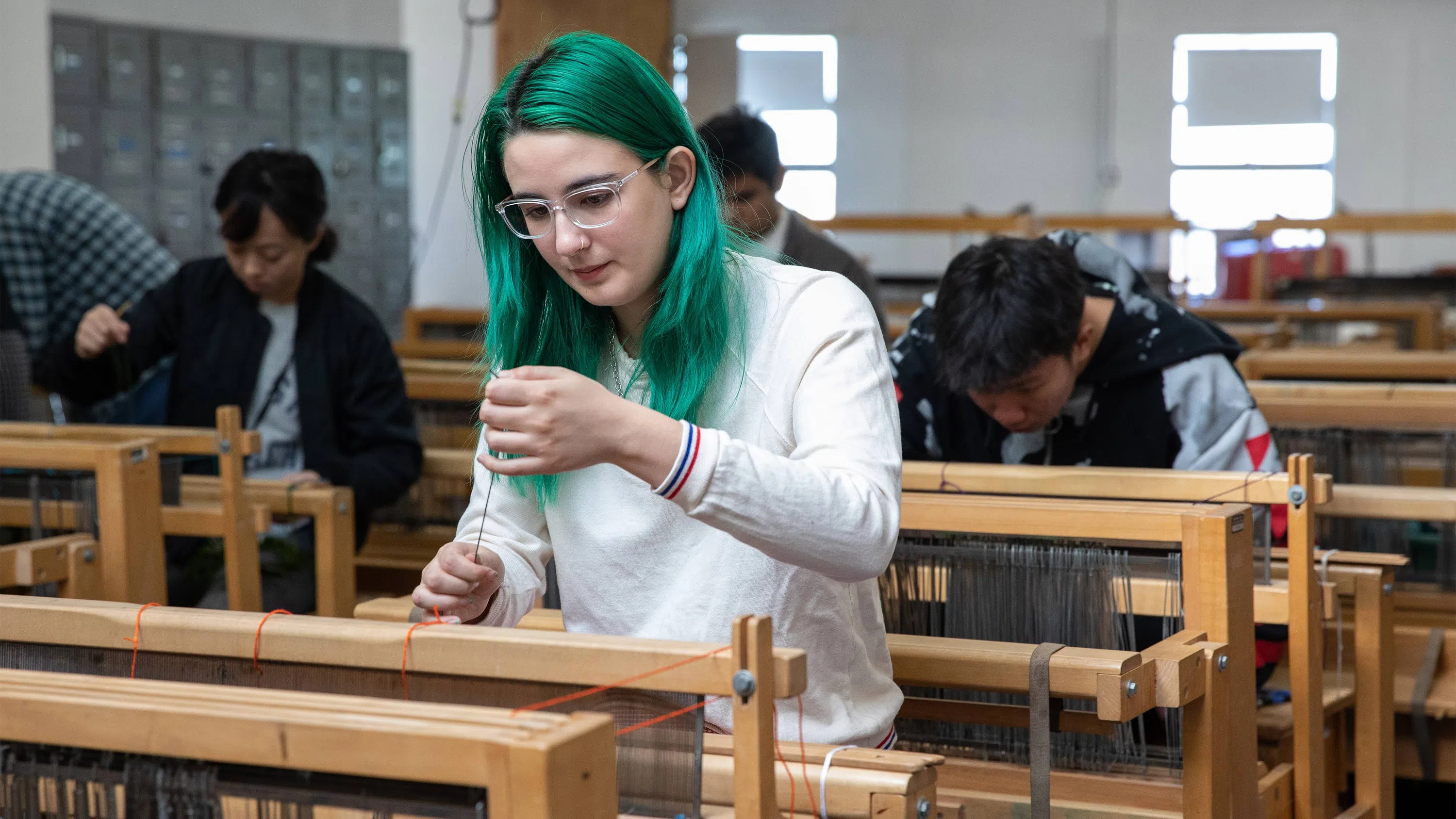 Students work at various looms in the Weaving Studio.