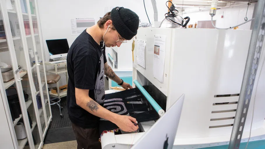 A student sets up work on the digital jacquard loom.