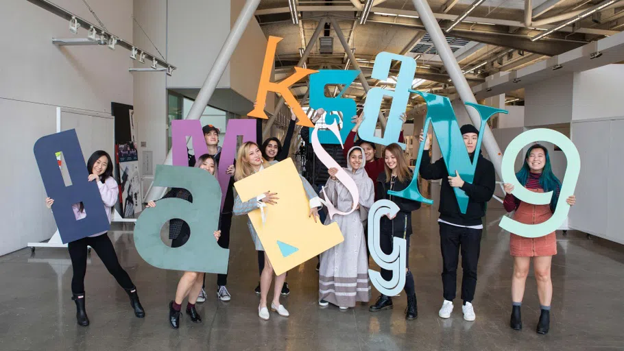 Ten students holding up giant letters in the air.