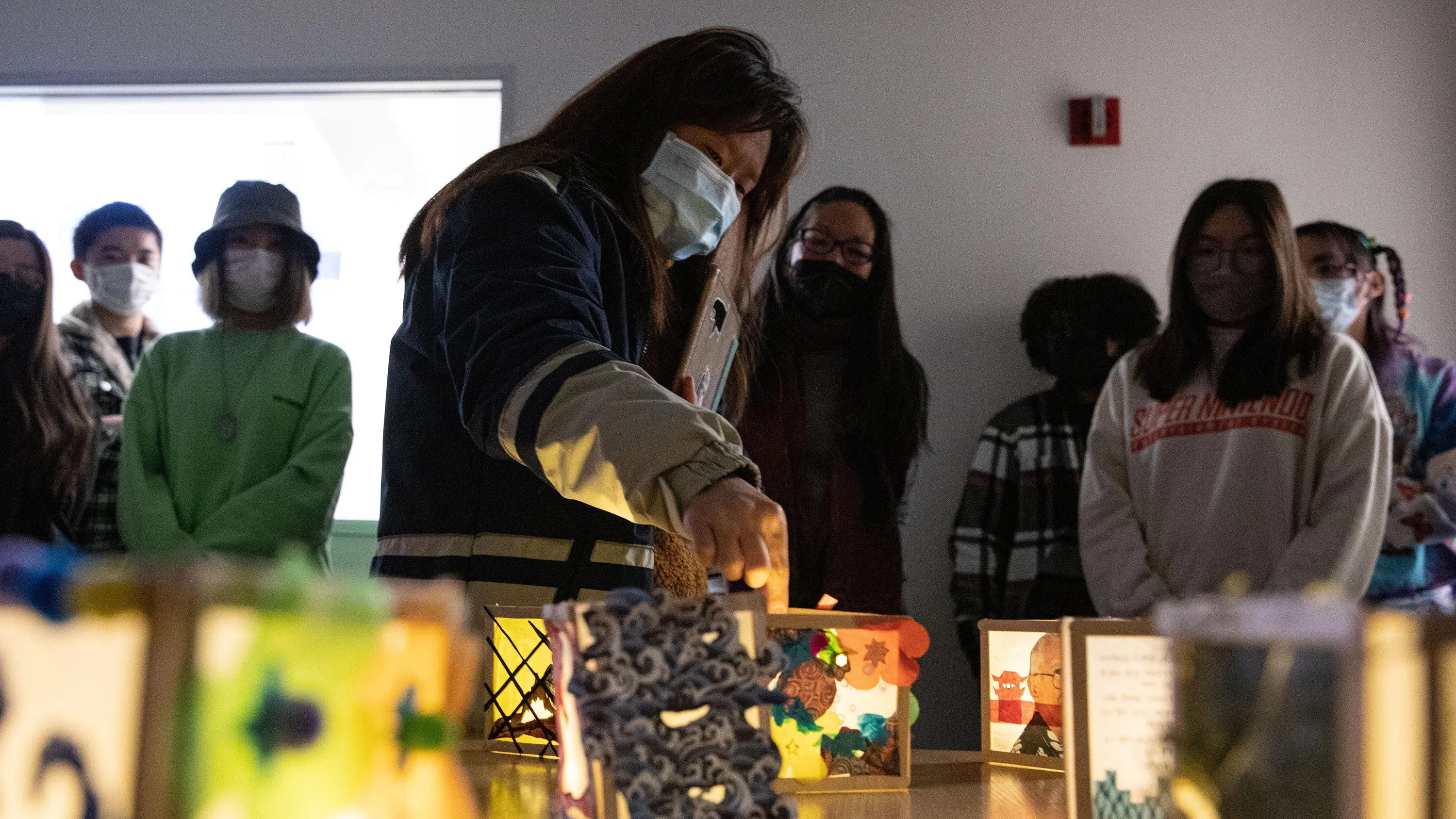 The Critical Studies class closely reviews paper lanterns, which illuminate a dimly-lit space.